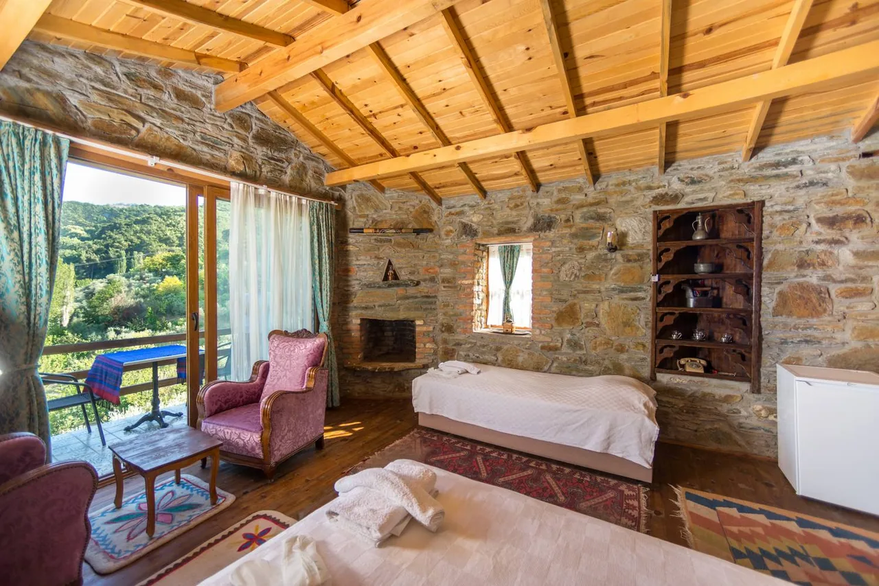 Lavanta Ev’in taş duvarları, ahşap tavanı, beyaz yatağı ve pembe koltuğu